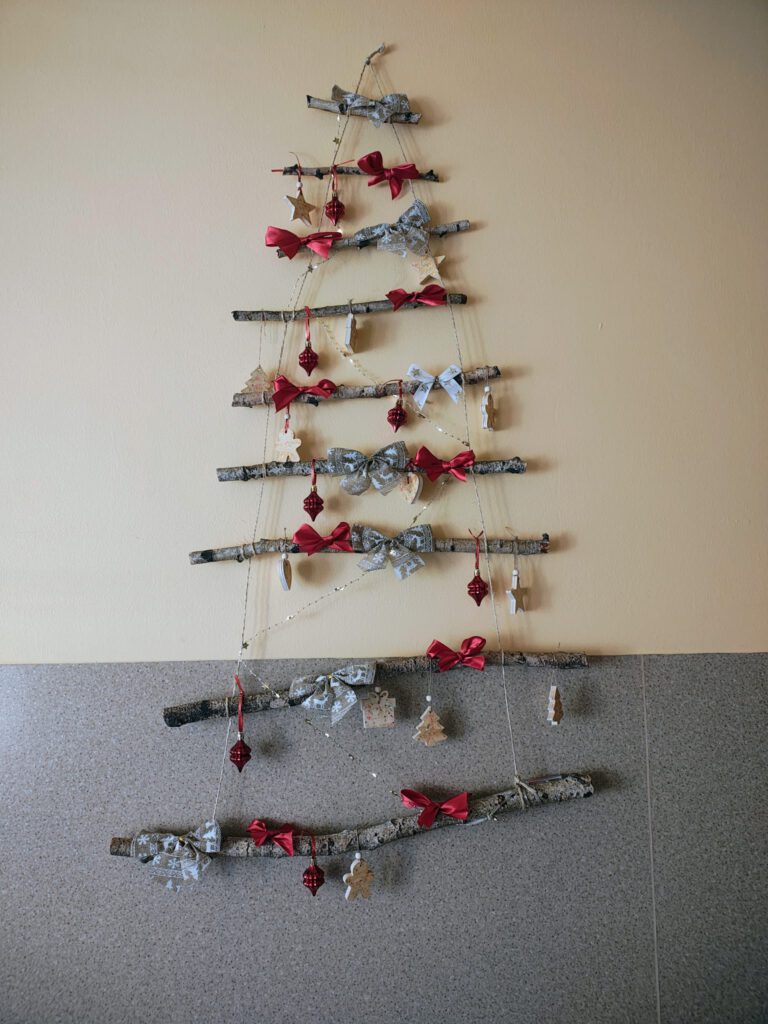 Dekoracja ścienna - choinka wykonana z suchych gałązek i i drewnianych dekoracji.