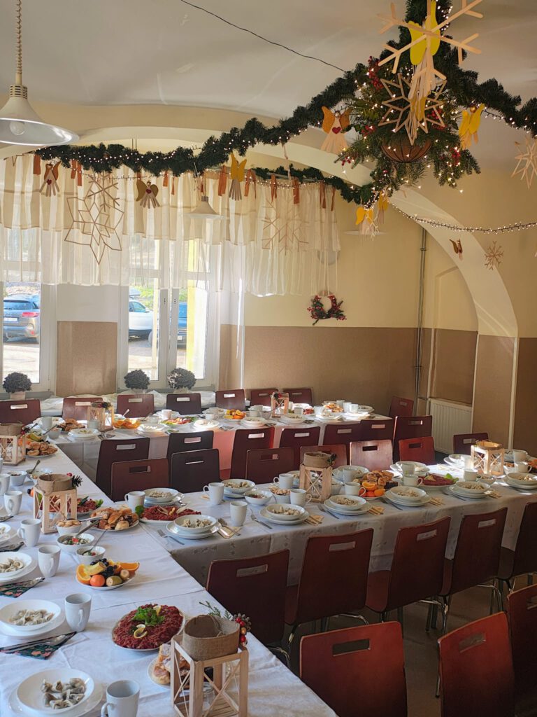świąteczna dekoracja stołówki - zielone girlandy i przygotowane stoły do wigilii.