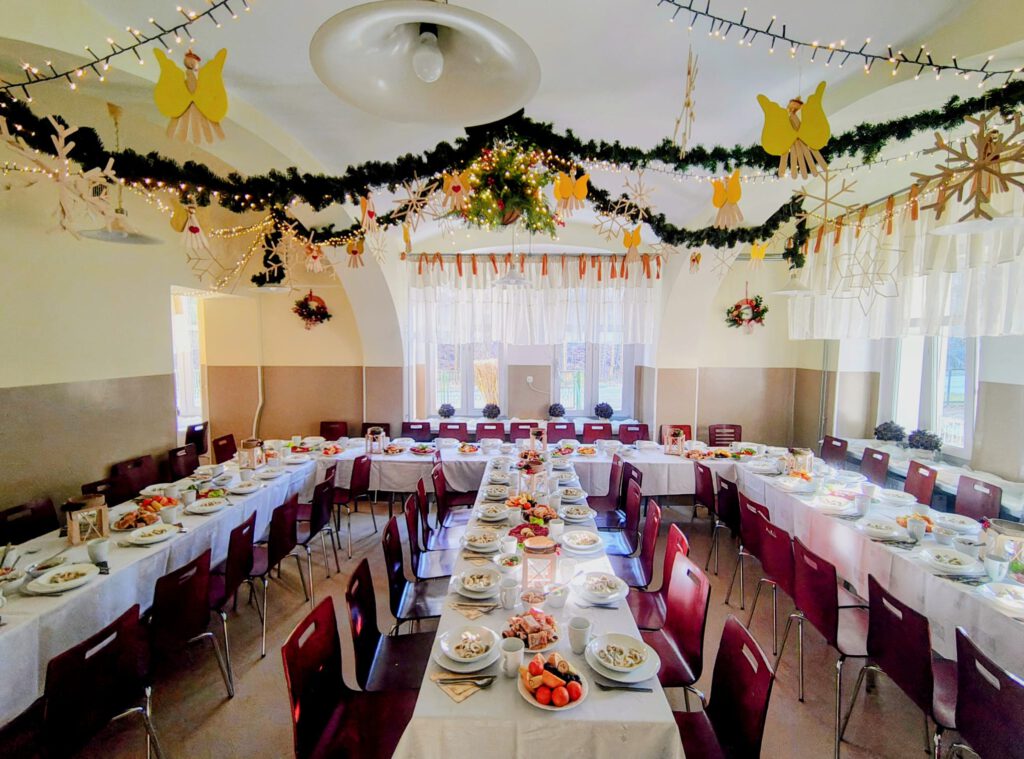 Świąteczna dekoracja stołówki - zielone girlandy i przygotowane stoły do wigilii.