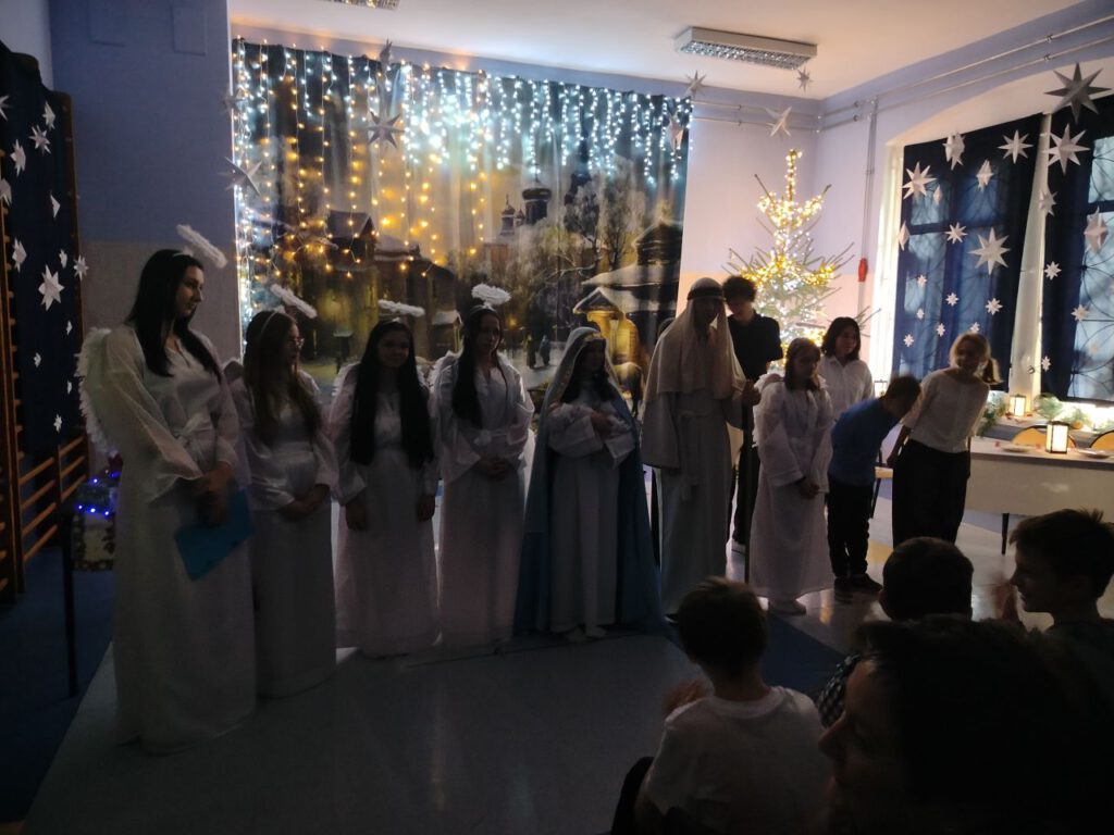 W szeregu stoją uczniowie przebrani za aniołów i recytują wiersze