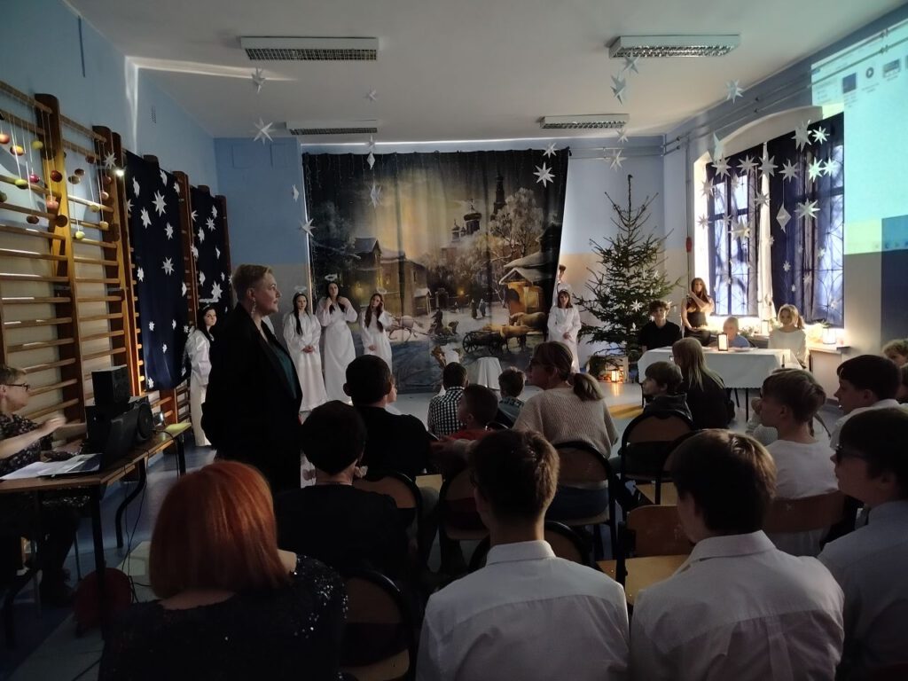 Pani Dyrektor składa wszystkim życzenia świąteczne, w oddali widać dziewczynki przebrane za anioły.