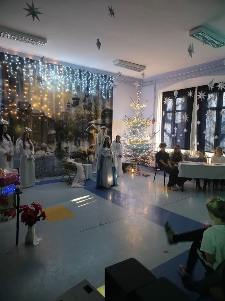 Zdjęcie przedstawia Maryję i Józefa. w głębi uczniowie siedzą przy stole przykrytym białym obrusem.