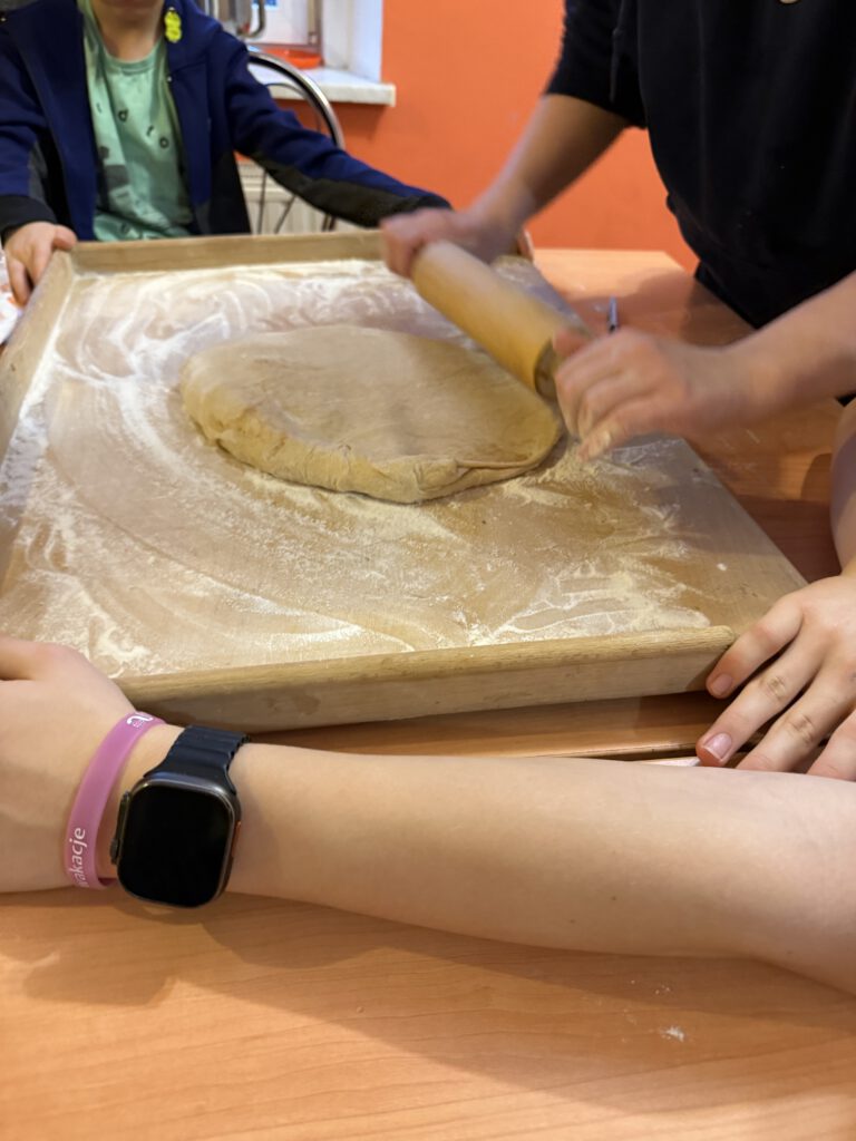 uczniowie wałkują ciasto na cynamonki