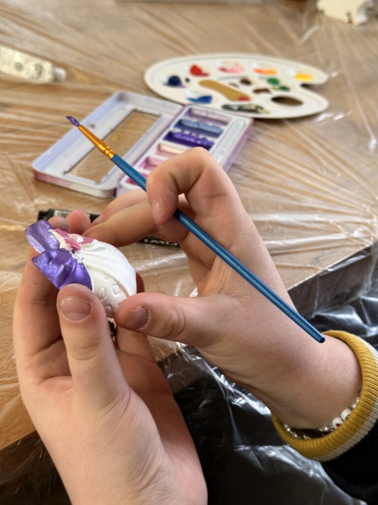 Uczniowie ozdabiają gipsowe figurki zajączków.